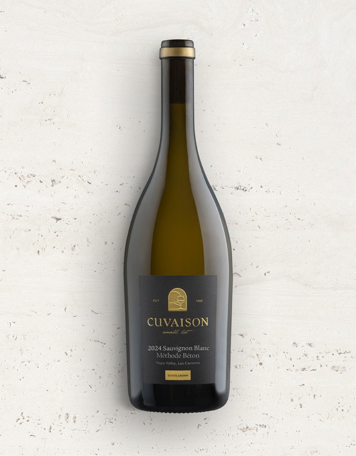 A bottle of 2024 Cuvaison Sauvignon Blanc, Méthode Béton stands upright against a light textured surface, featuring a dark label with gold accents and clear, simple text.