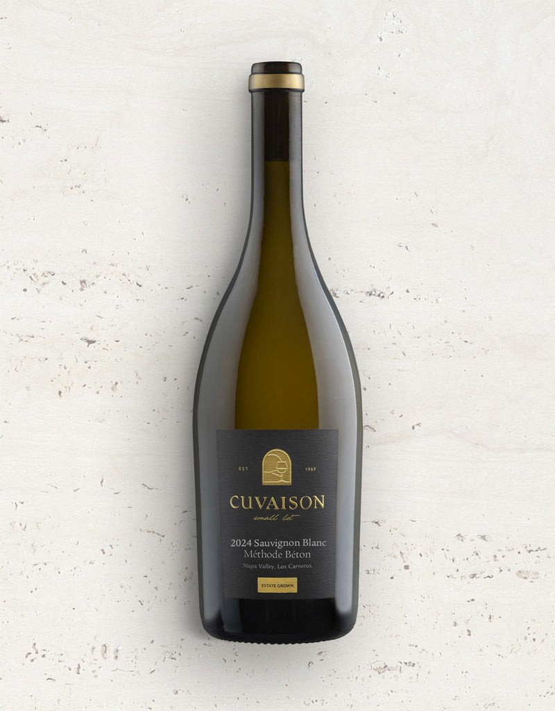 A bottle of 2024 Cuvaison Sauvignon Blanc, Méthode Béton stands upright against a light textured surface, featuring a dark label with gold accents and clear, simple text.