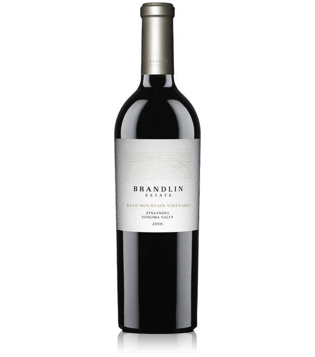 A bottle of 2019 Brandlin Estate Zinfandel, Bald Mountain Vineyard, with a silver and white label, dark glass body, and metallic silver capsule.