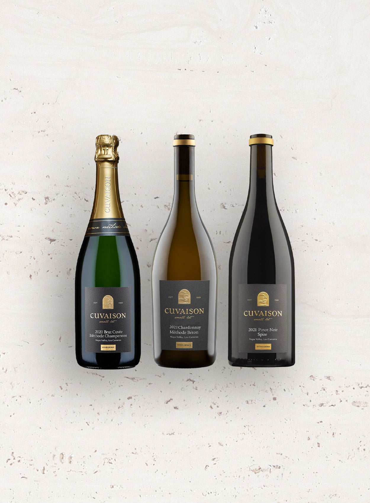 Six Cuvaison 6 Bottle Club wines stand upright against a light, textured backdrop, featuring sparkling wine, Chardonnay, and Pinot Noir with dark labels and gold accents.