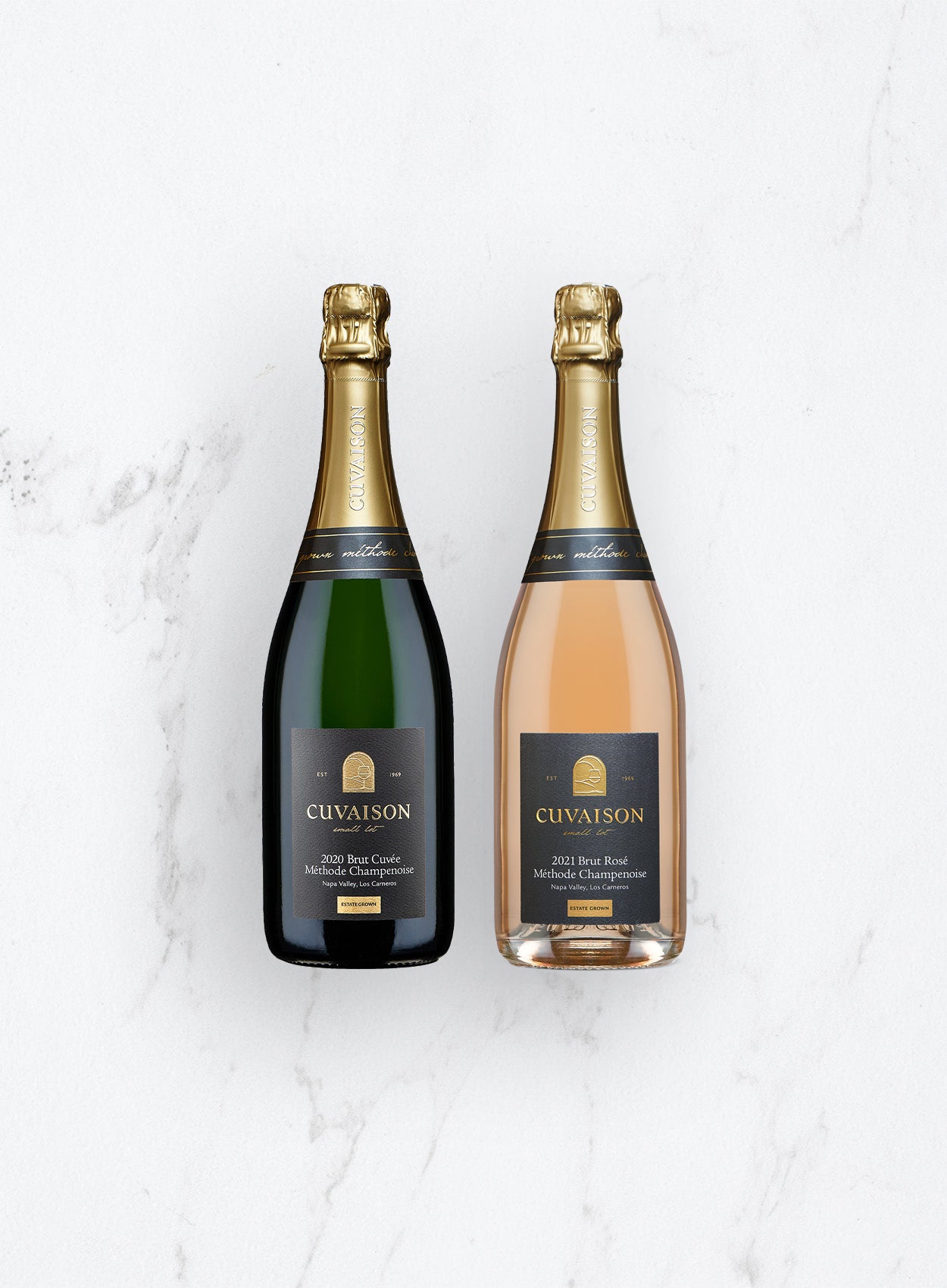 The Cuvaison Sparkling Duo, featuring a 2020 Brut Cuvée and a 2021 Brut Rosé with gold-foiled necks and black labels, are side by side on a white marble surface.