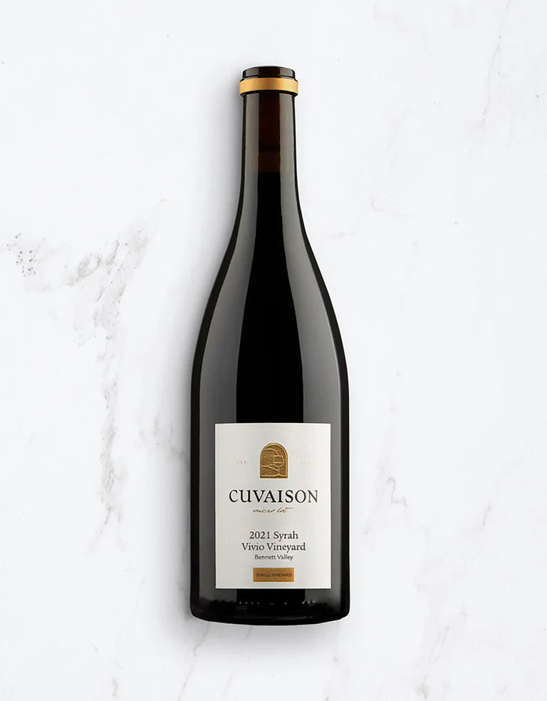 A single dark glass wine bottle with a cream label reading Cuvaison 2021 Syrah Vivo Vineyard stands upright on a white marble surface.