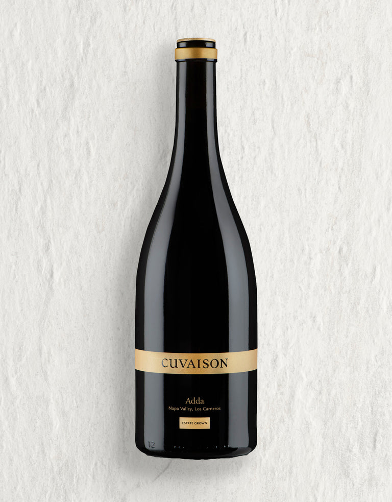 A dark glass wine bottle with a gold label reading 2022 Cuvaison Pinot Noir, Adda, Napa Valley, Los Carneros, Estate Grown, stands upright against a light textured background.