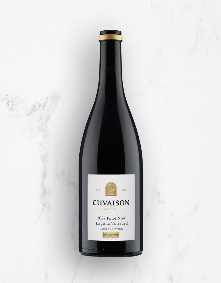 A bottle of 2022 Cuvaison Pinot Noir, Laguna Vineyard, stands upright on white marble. It features a black and gold cap and a white label with gold and black text.