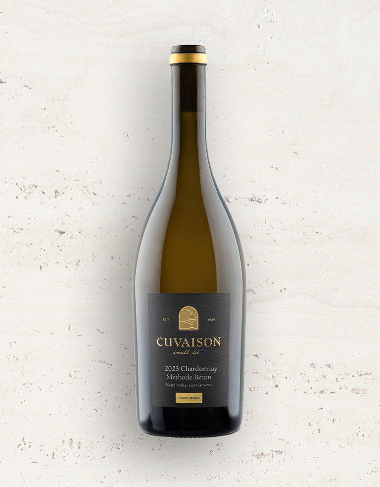 A bottle of 2023 Cuvaison Chardonnay, Méthode Béton stands upright against a light, textured background. Its dark label features gold and white text.