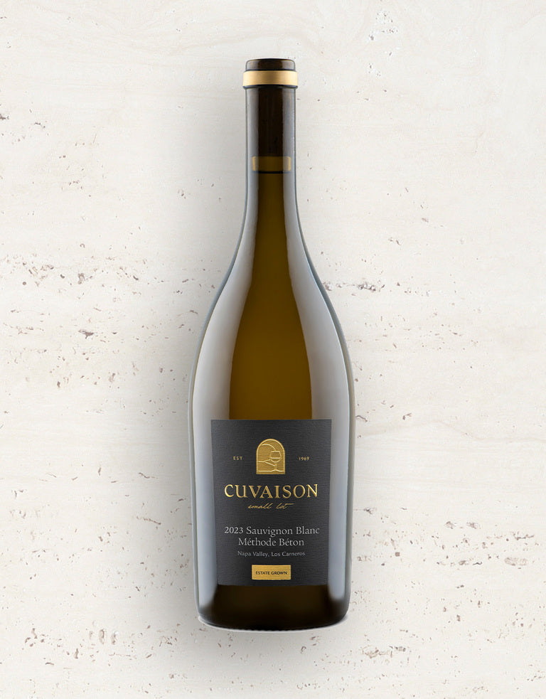 A bottle of 2023 Cuvaison Sauvignon Blanc, Méthode Béton stands upright with a dark label and gold text, set against a light, speckled background.