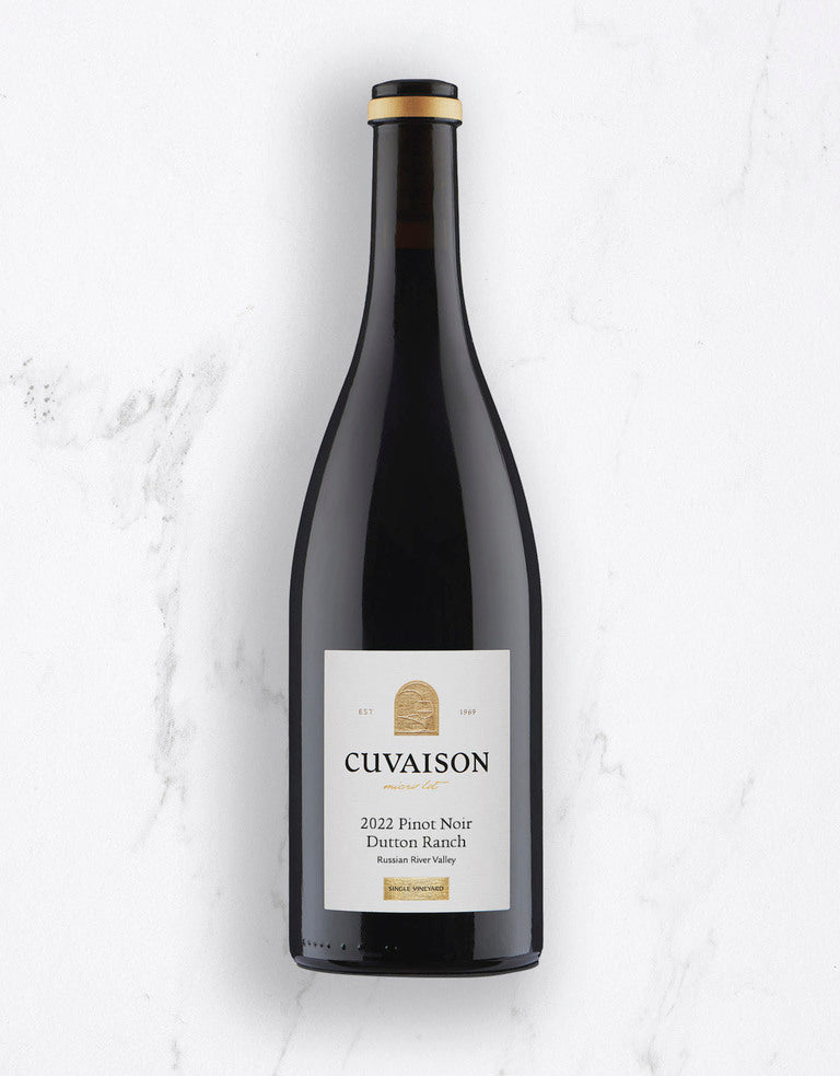 A bottle of 2022 Cuvaison Pinot Noir, Dutton Ranch stands upright on a white marble surface. The label features white with gold and black text.