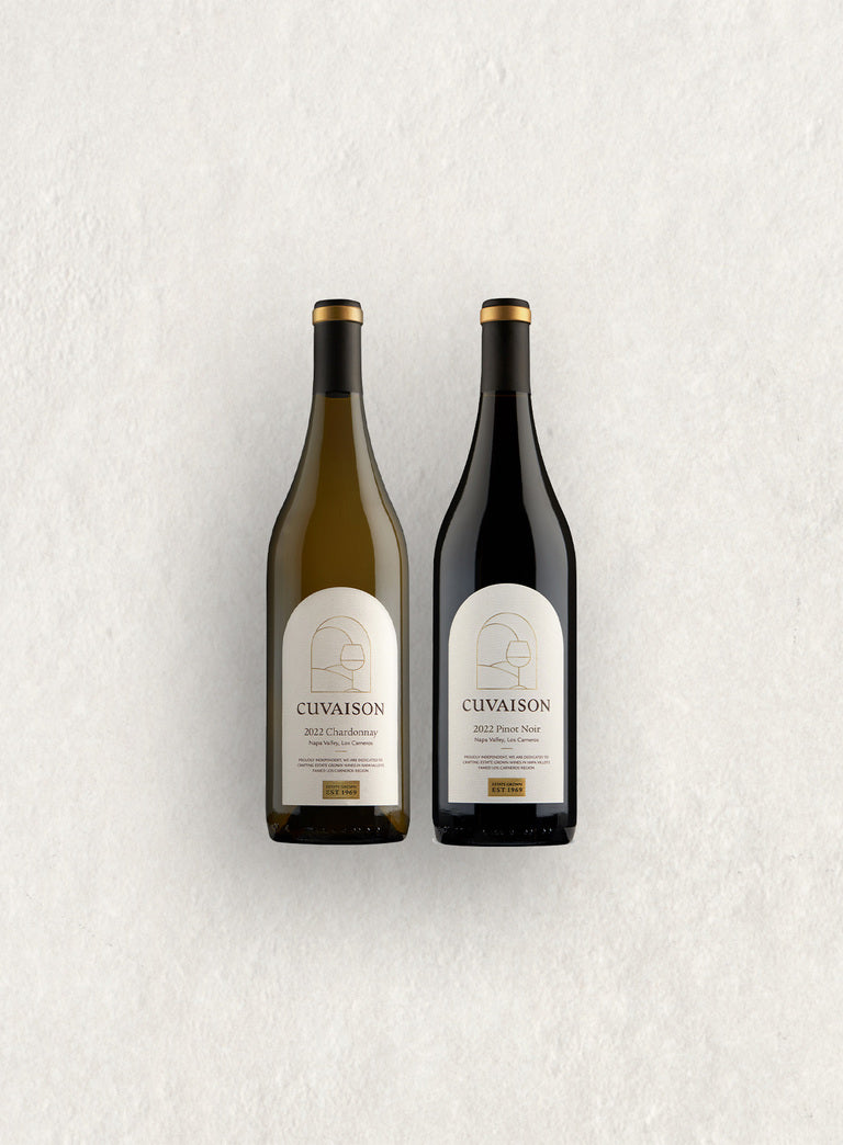 The Cuvaison Classics Duo features two wine bottles—2022 Chardonnay on the left and 2022 Pinot Noir on the right—each with matching white and gold-accented “CUVAISON” labels, displayed side by side on a light, textured surface.