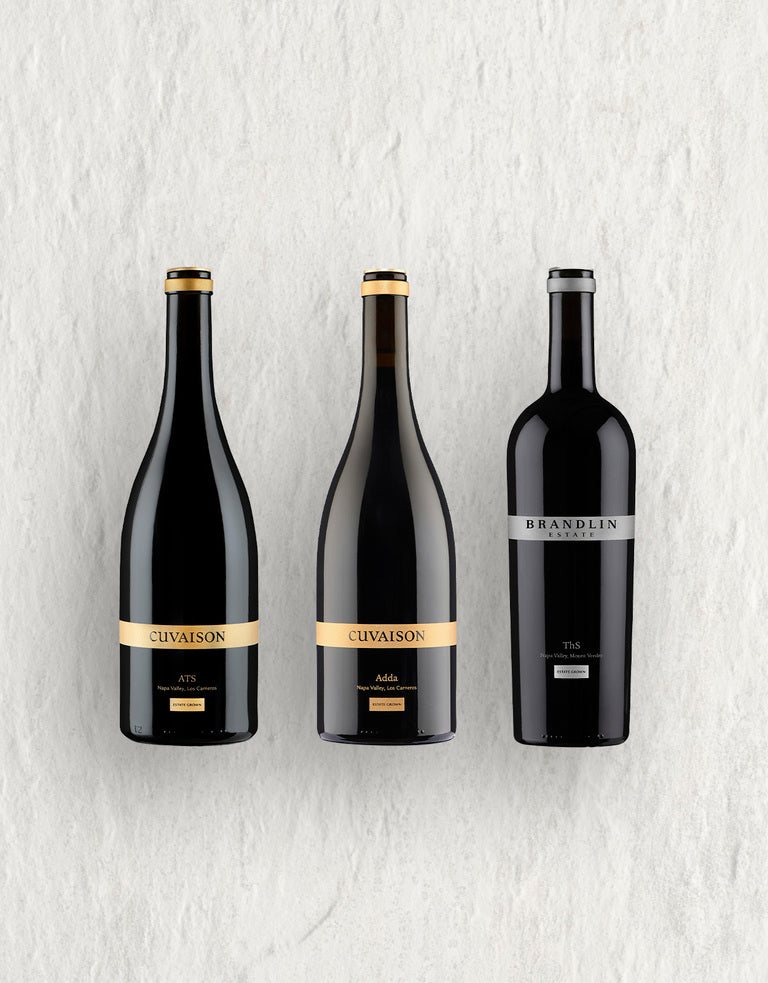 The Legacy Trio features three upright red wine bottles against a light textured background: two labeled CUVAISON with gold accents and one labeled BRANDLIN with a silver label.