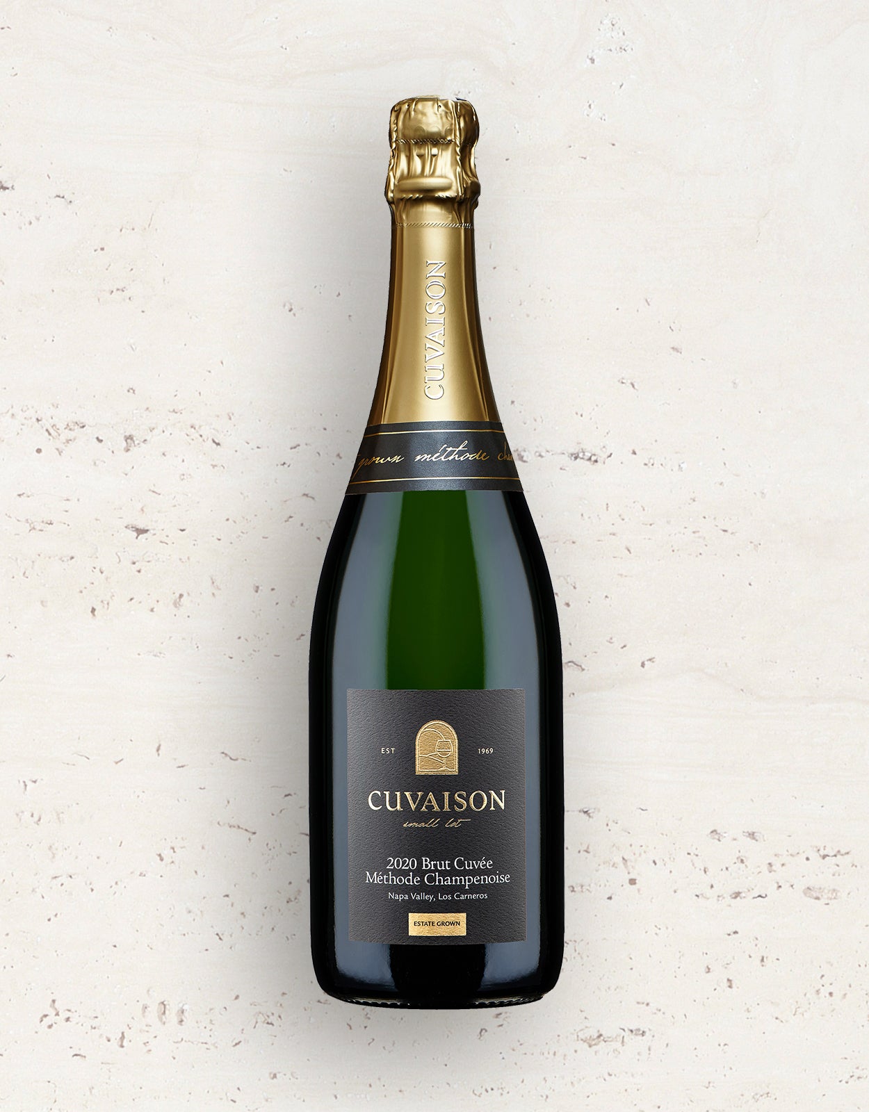 A bottle of 2020 Cuvaison Brut Cuvée, Méthode Champenoise sparkling wine stands upright against a light, textured background, featuring a gold foil top and a black label with gold and white text.