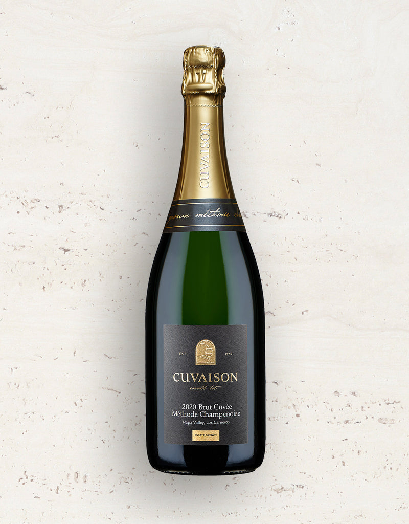 A bottle of 2020 Cuvaison Brut Cuvée, Méthode Champenoise sparkling wine stands upright against a light, textured background, featuring a gold foil top and a black label with gold and white text.